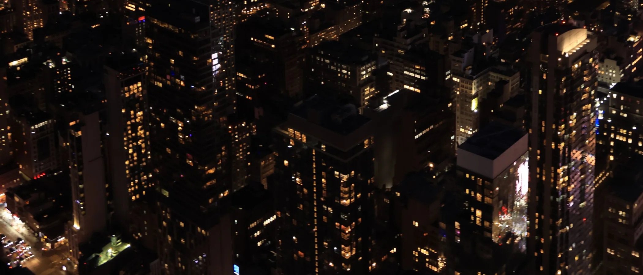 A chauffeured luxury sedan waiting outside a New York City landmark at dusk